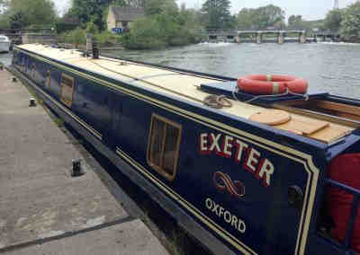 Looking down the length of College Cruisers' Oxford Blue luxury hire narrowboat Exeter moored on the Oxford Canal.